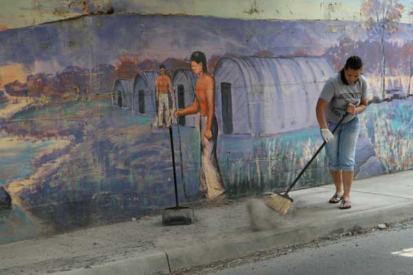 Stephanie Stewart sweeping the sidewalks under the trestle.